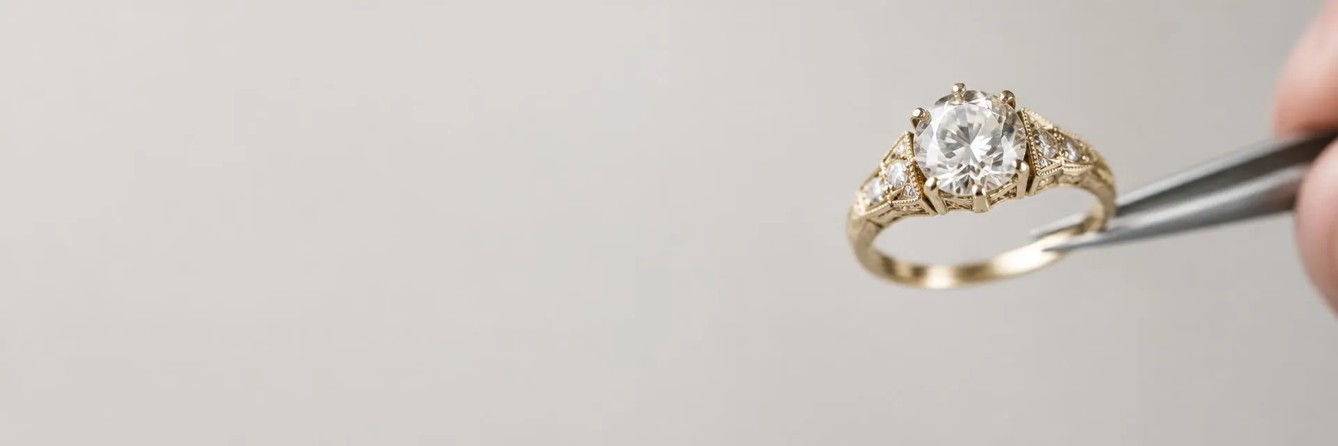 Vintage gold diamond ring held by jeweler's tweezers